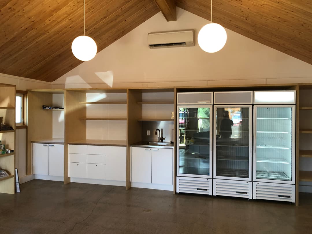 Modern kitchen interior with wooden ceiling, sleek cabinetry, and a large refrigerator unit.
