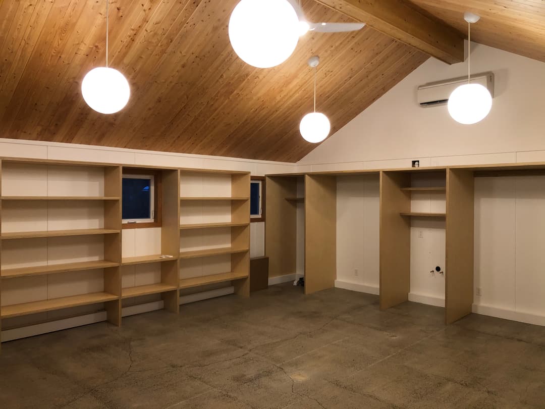 spacious modern room with wooden ceiling, shelving units, and round pendant lights