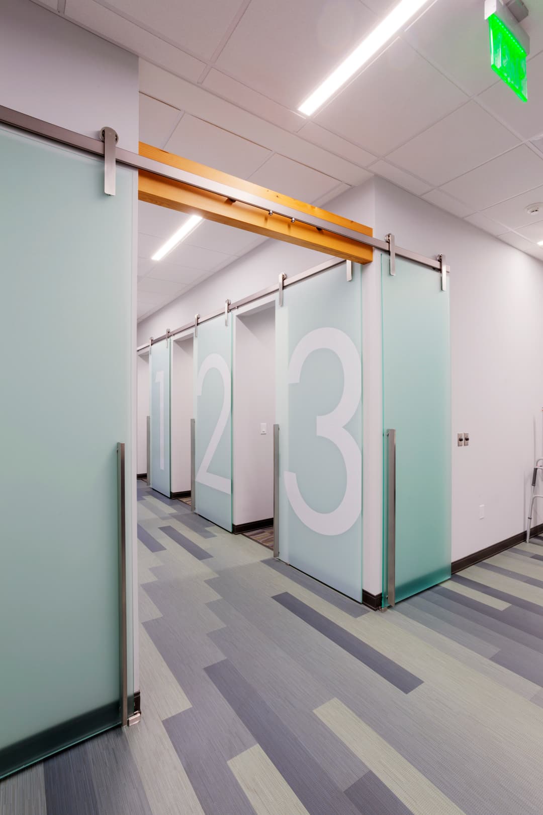 Modern hallway with sliding glass doors numbered 1, 2, and 3, featuring sleek design elements.