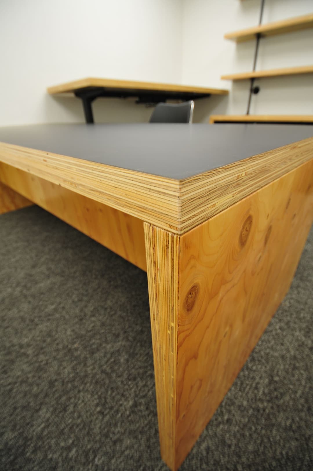 Modern wooden desk with a sleek black surface in a minimalist workspace setting.