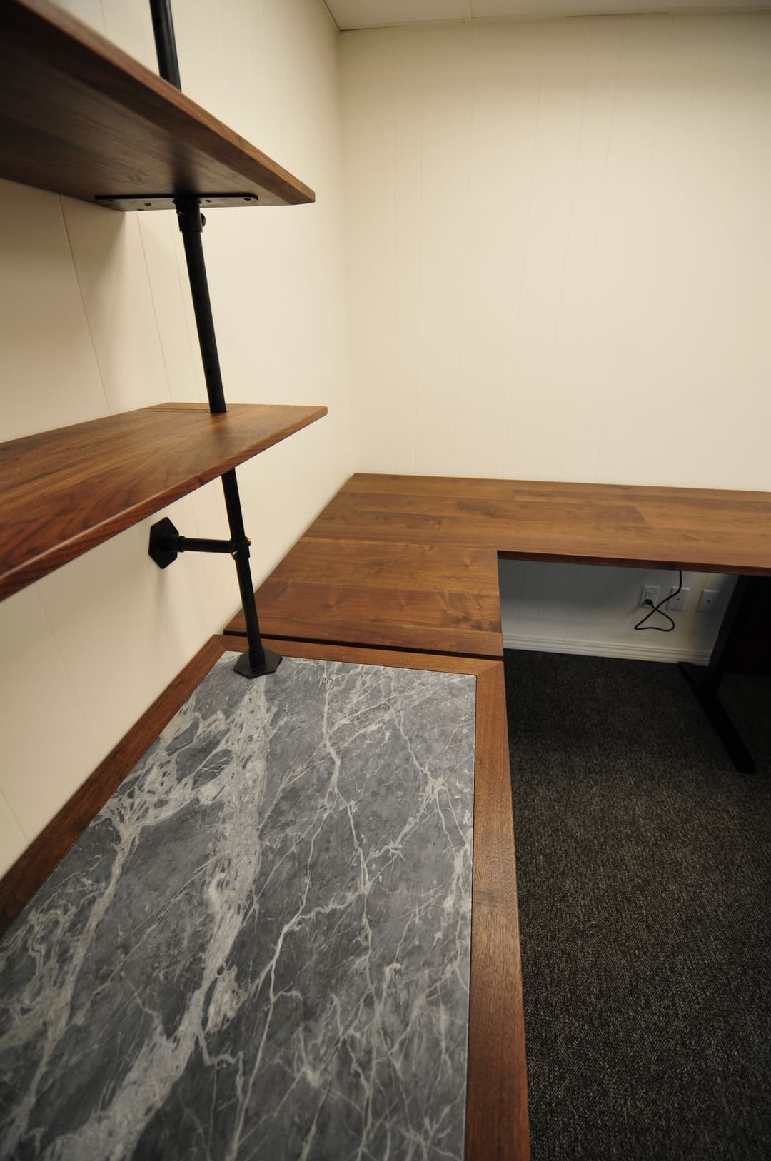 Modern office setup featuring wooden shelves and a sleek marble desk with a minimalistic design.