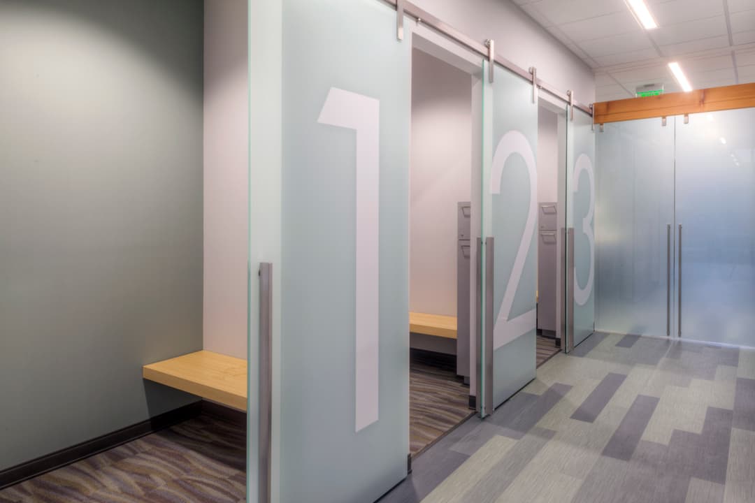 Modern office design with glass partitions featuring numbers 1, 2, and 3 on sliding doors.