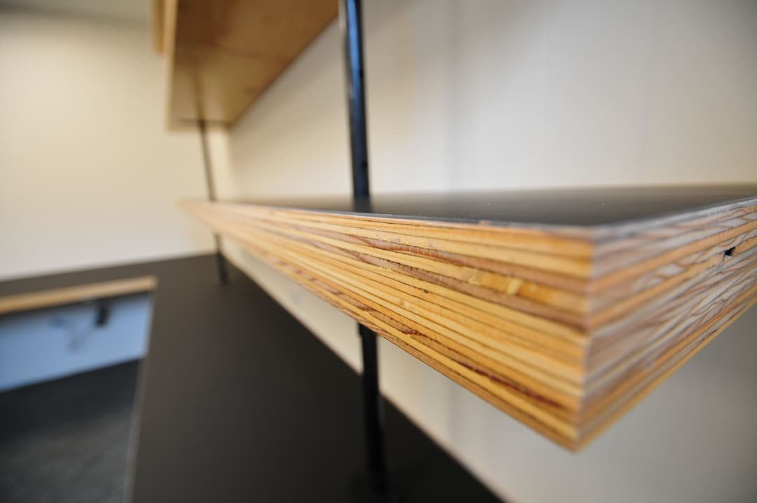 Close-up of layered wooden shelf on a modern black surface with sleek metal supports.