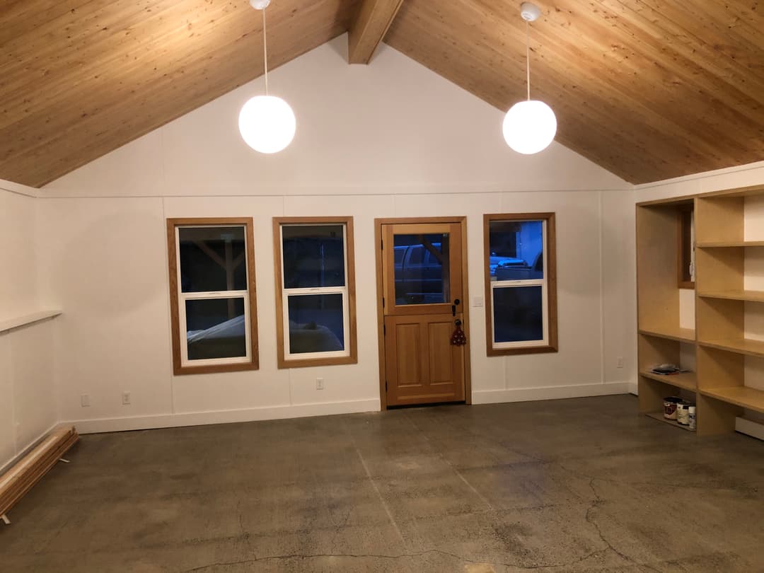 Cozy interior of a modern room with wooden beams, large windows, and a front door.