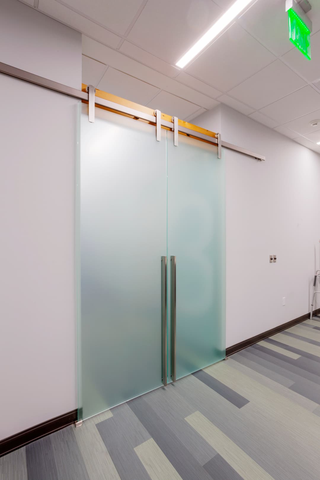 Frosted glass sliding door with wooden hardware in modern office interior.