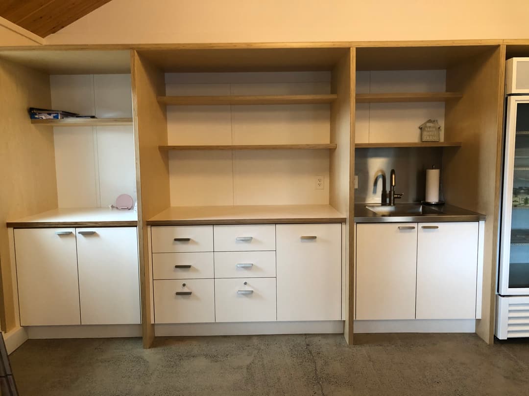 Modern kitchen cabinetry with open shelves and sink area in a minimalist design.