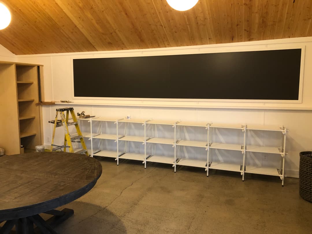 Modern interior with a black chalkboard, white shelves, and a wooden ceiling.