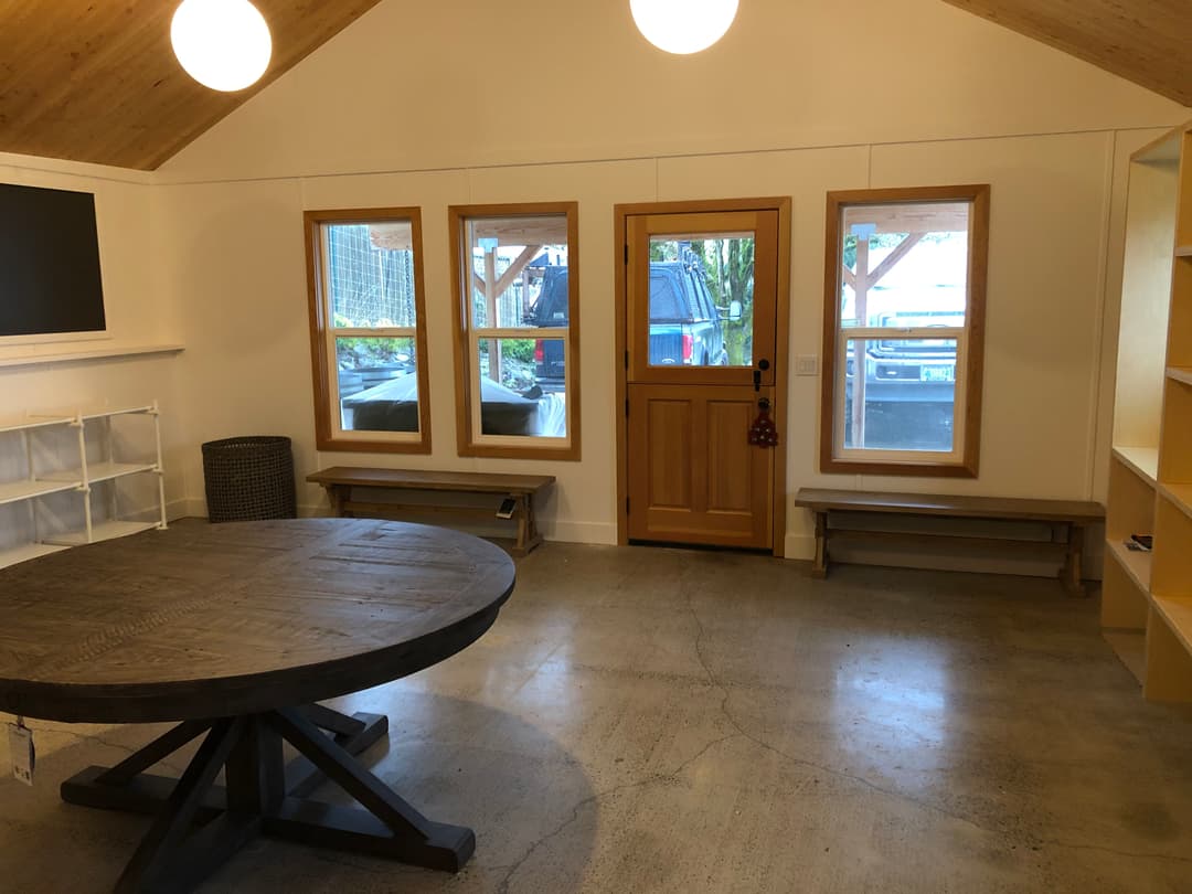 Cozy interior of a modern room with large windows, wooden door, and round table.