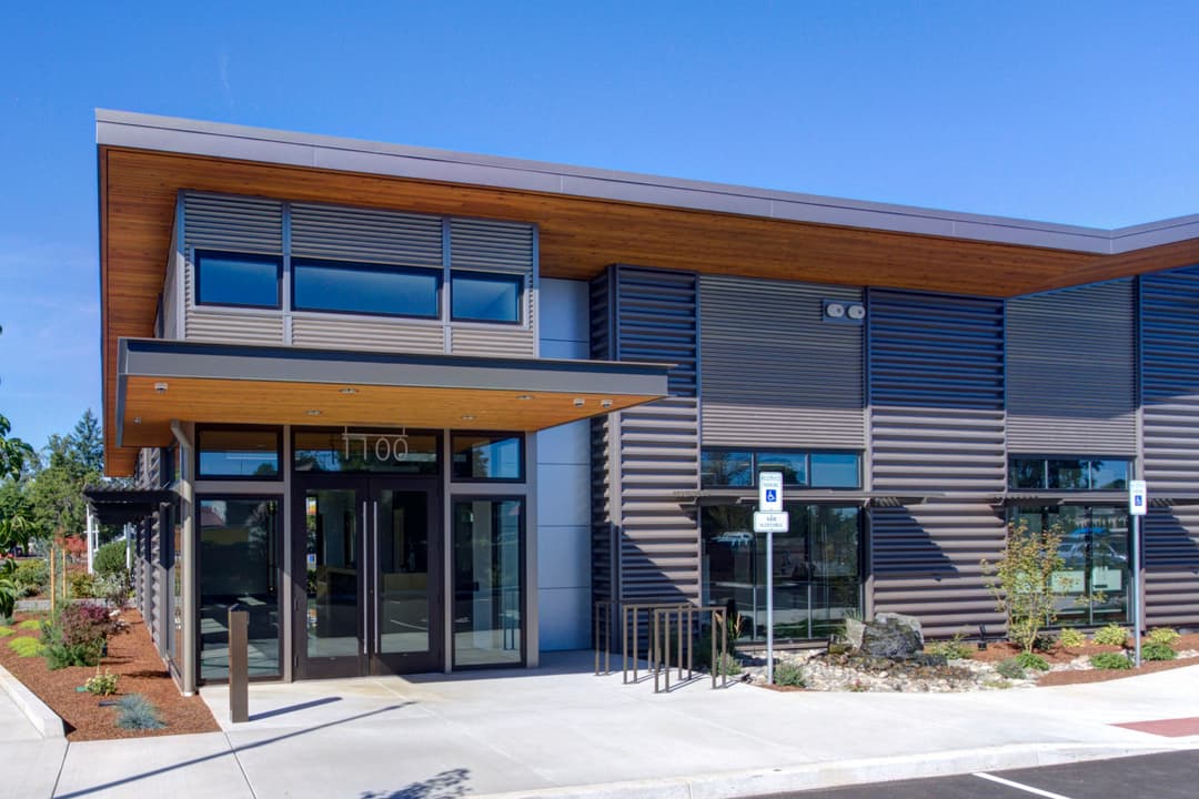 Modern commercial building with large glass entrance and landscaped surroundings.