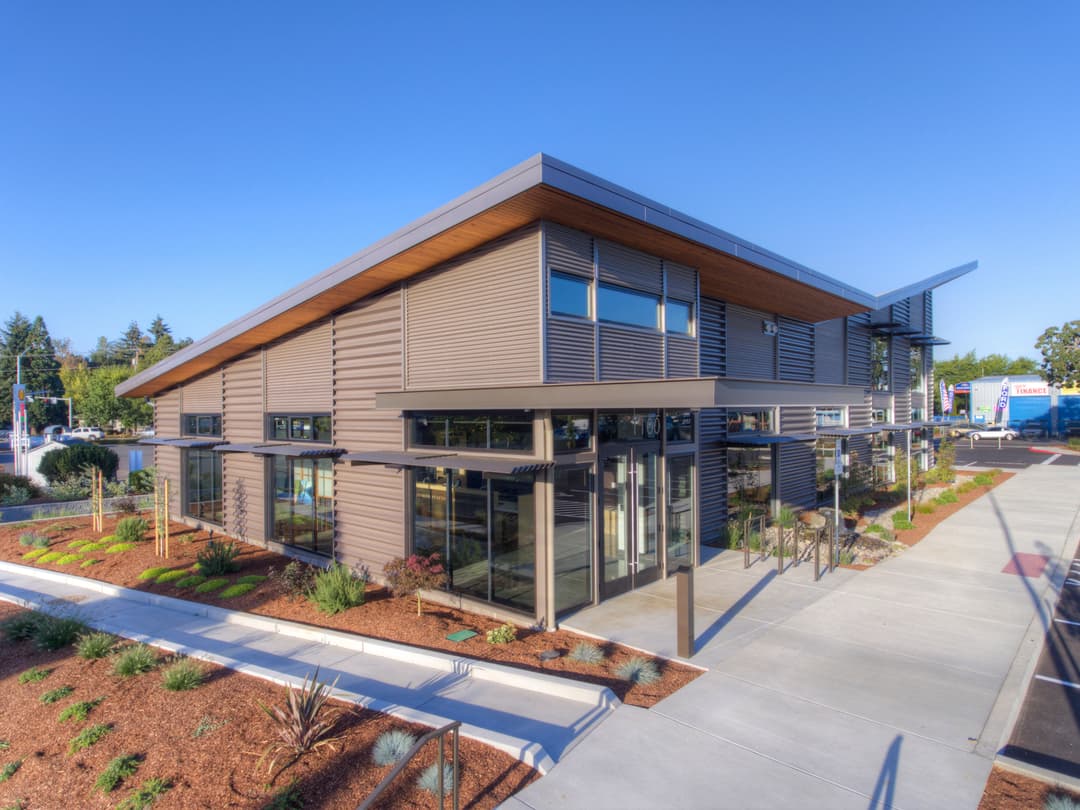 Modern eco-friendly commercial building with large windows and landscaped surroundings.