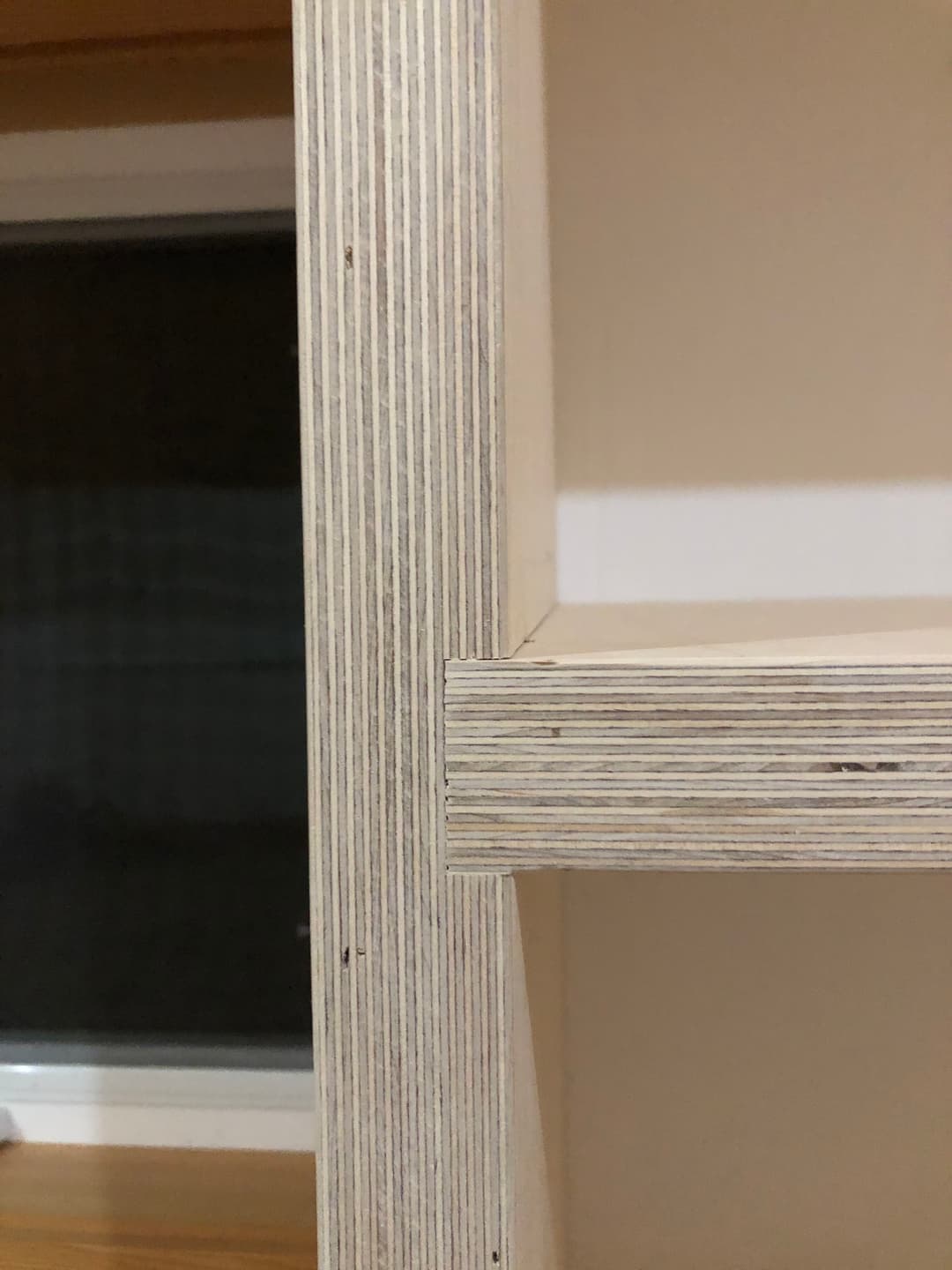 Close-up of a laminated wood shelf corner, showcasing layered plywood construction.