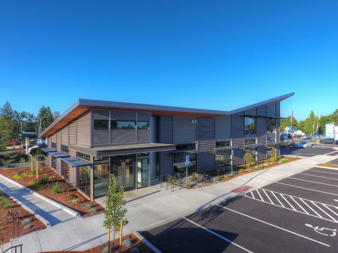 Modern commercial building with sleek design, large windows, and landscaped parking area.