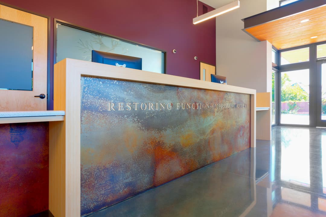 Reception desk at a healing center with "Restoring Function" signage and modern design.