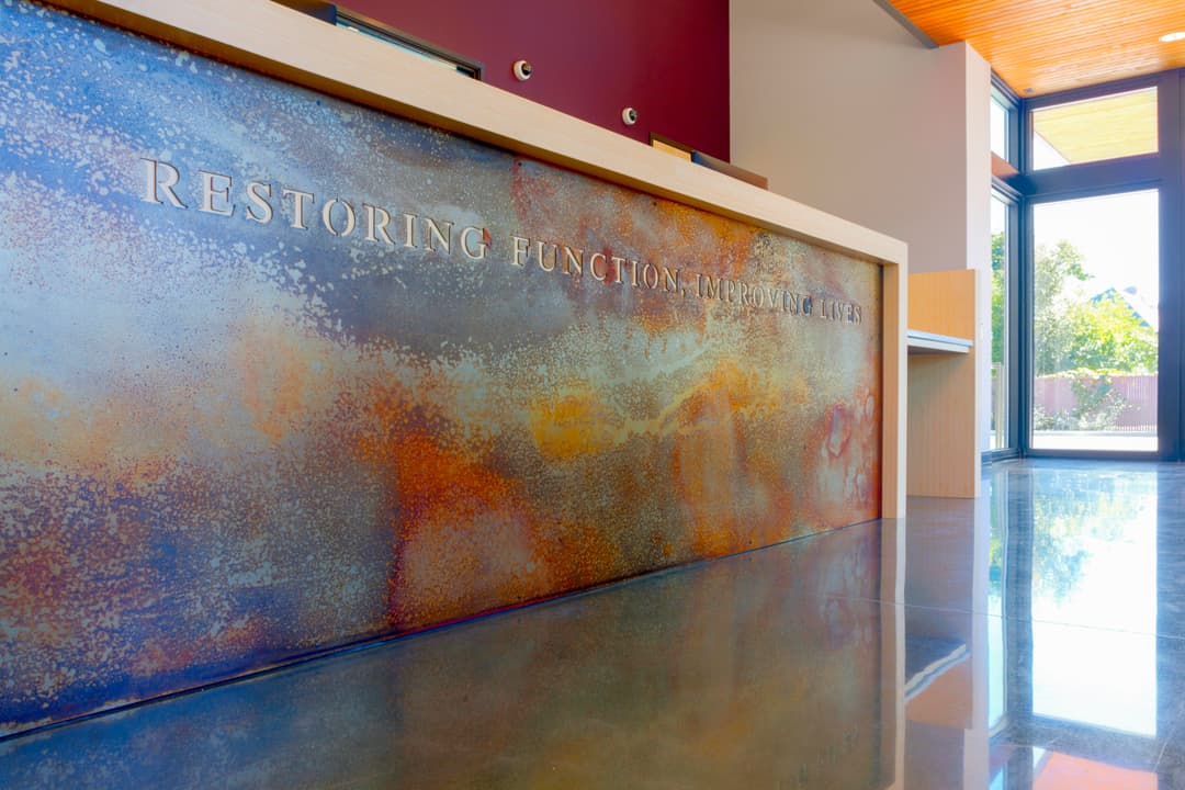 Modern reception desk with "Restoring Function, Improving Lives" inscription in a stylish office.