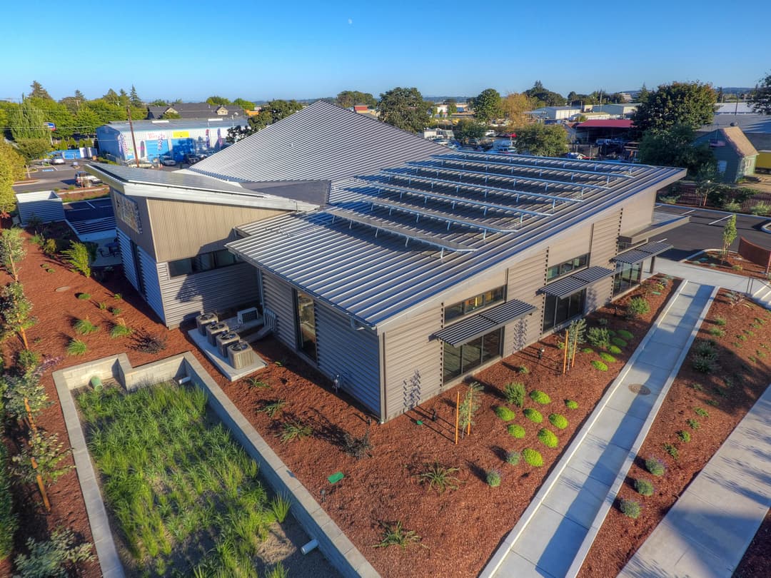 Modern building with solar panels, landscaped garden, and clear blue sky. Sustainable architecture.