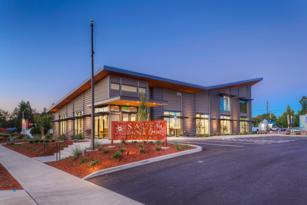 Modern Salem bank building with large windows and landscaped entrance at twilight.