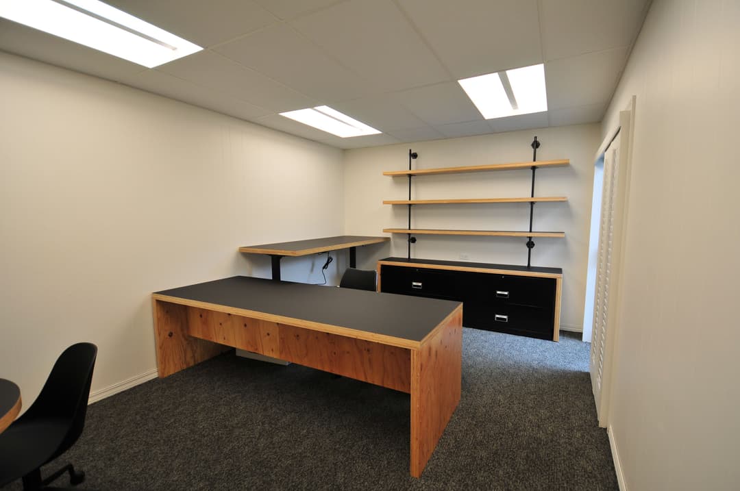 Modern office interior featuring a wooden desk, shelves, and minimalistic design.