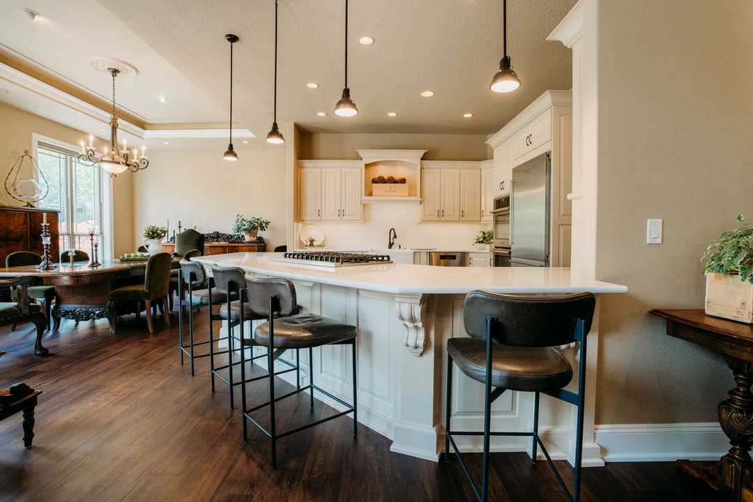 Modern kitchen with white cabinetry, island seating, and elegant pendant lighting.
