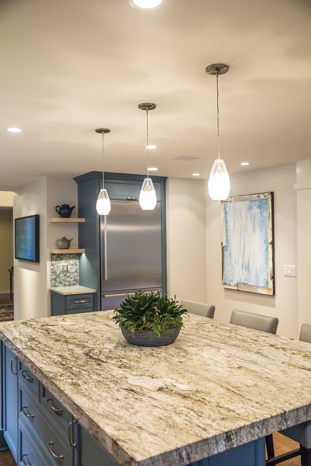 Modern kitchen with granite island, pendant lights, and stainless steel appliances.