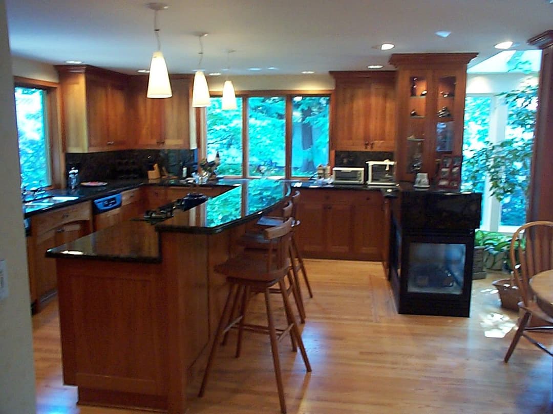 Modern kitchen with wooden cabinetry, granite countertops, and large windows for natural light.