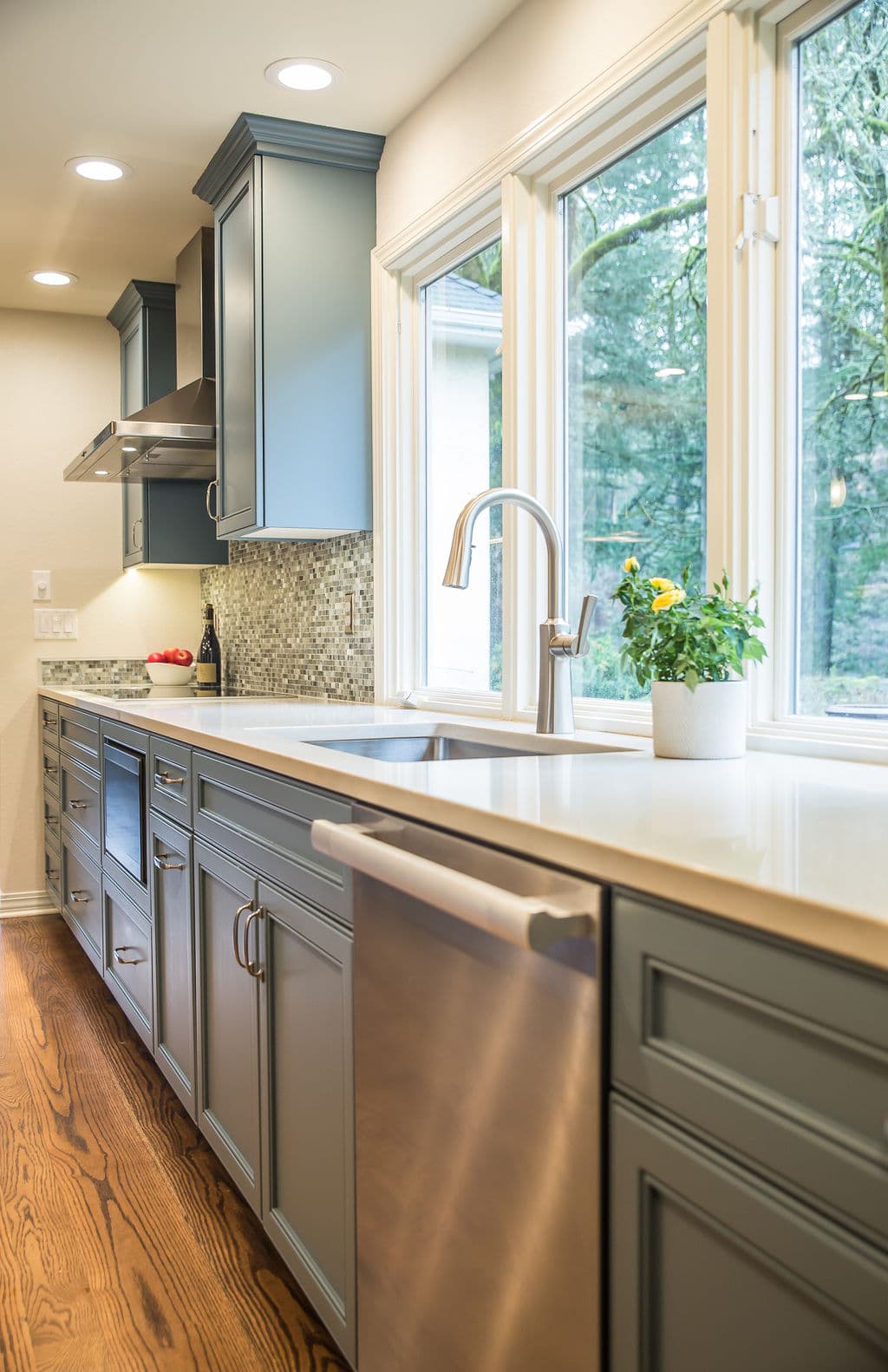 Modern kitchen with sleek gray cabinets, stainless steel appliances, and large windows.