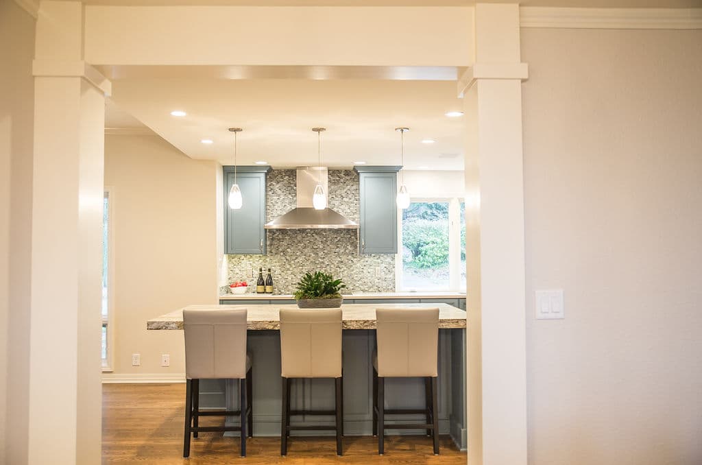 Modern kitchen with gray cabinets, stone backsplash, and a stylish island with bar stools.