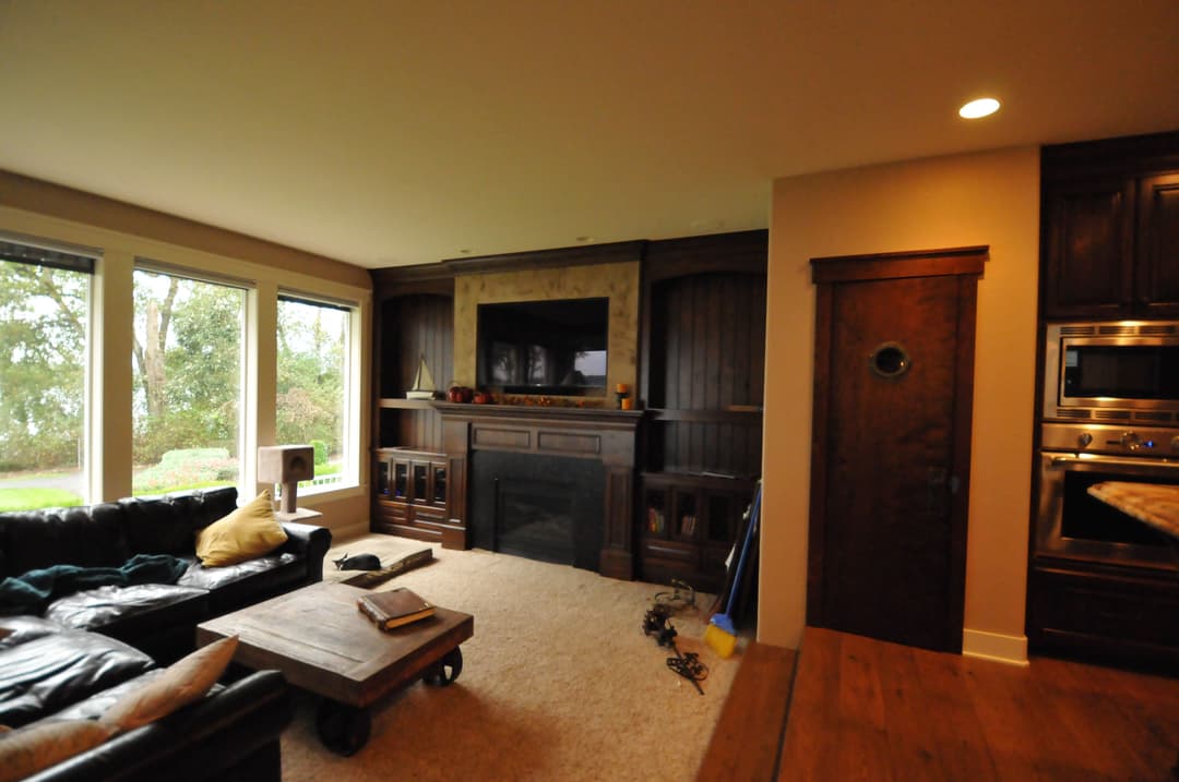 Modern living room with a dark wood entertainment center, large windows, and a cozy sofa.