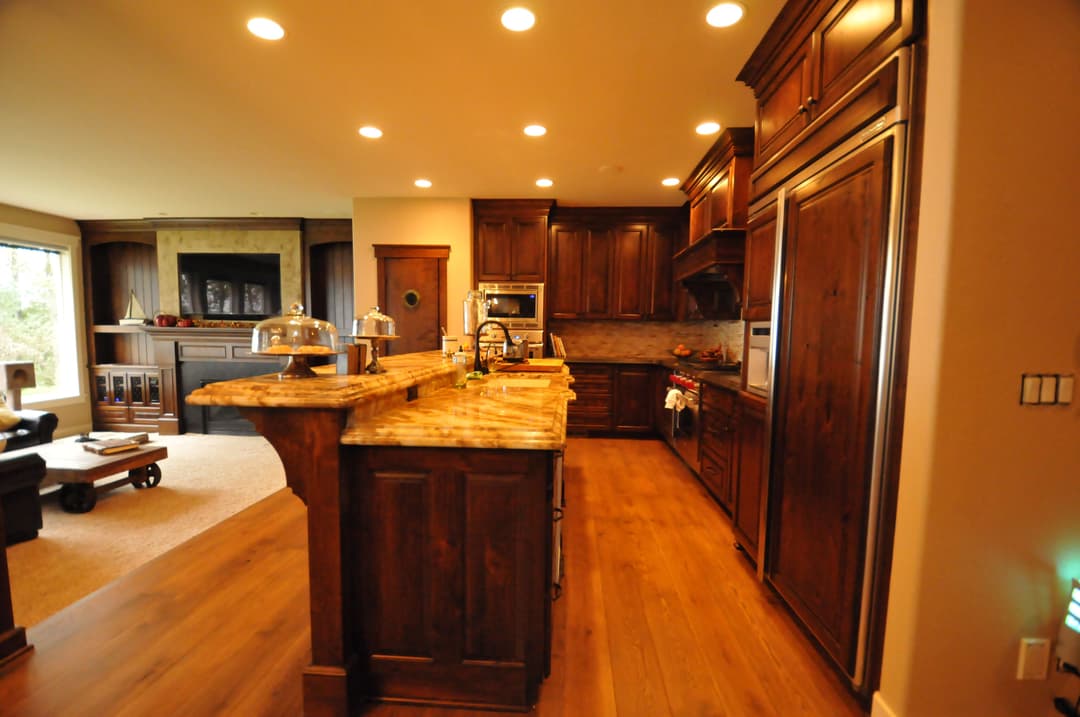 Modern kitchen with dark wood cabinetry, granite countertops, and warm lighting accents.