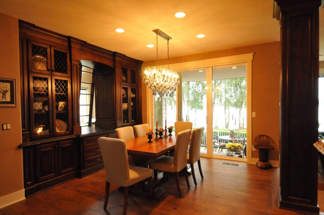 Elegant dining room featuring a chandelier, wooden table, and glass door to a patio.