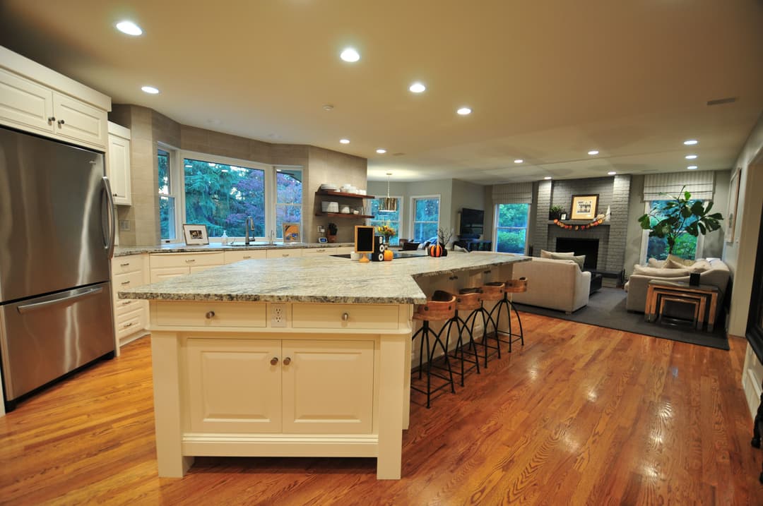 Modern kitchen with granite island, stainless steel appliances, and open living area.