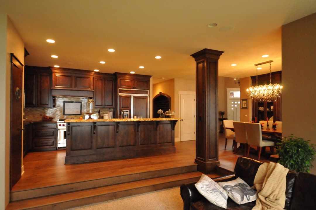 Modern kitchen with dark wood cabinets, stainless steel appliances, and a stylish dining area.