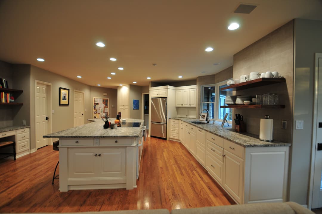 Modern kitchen featuring an island, granite countertops, white cabinets, and hardwood floors.