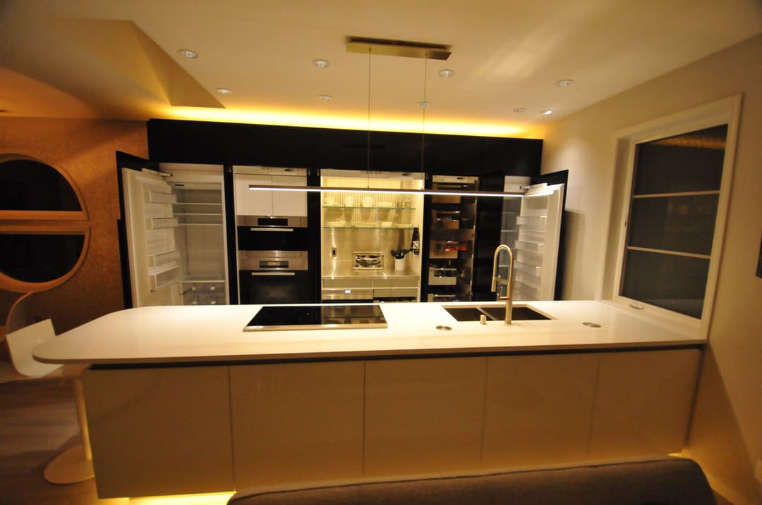 Modern kitchen with sleek cabinetry, illuminated shelving, and stylish appliances.