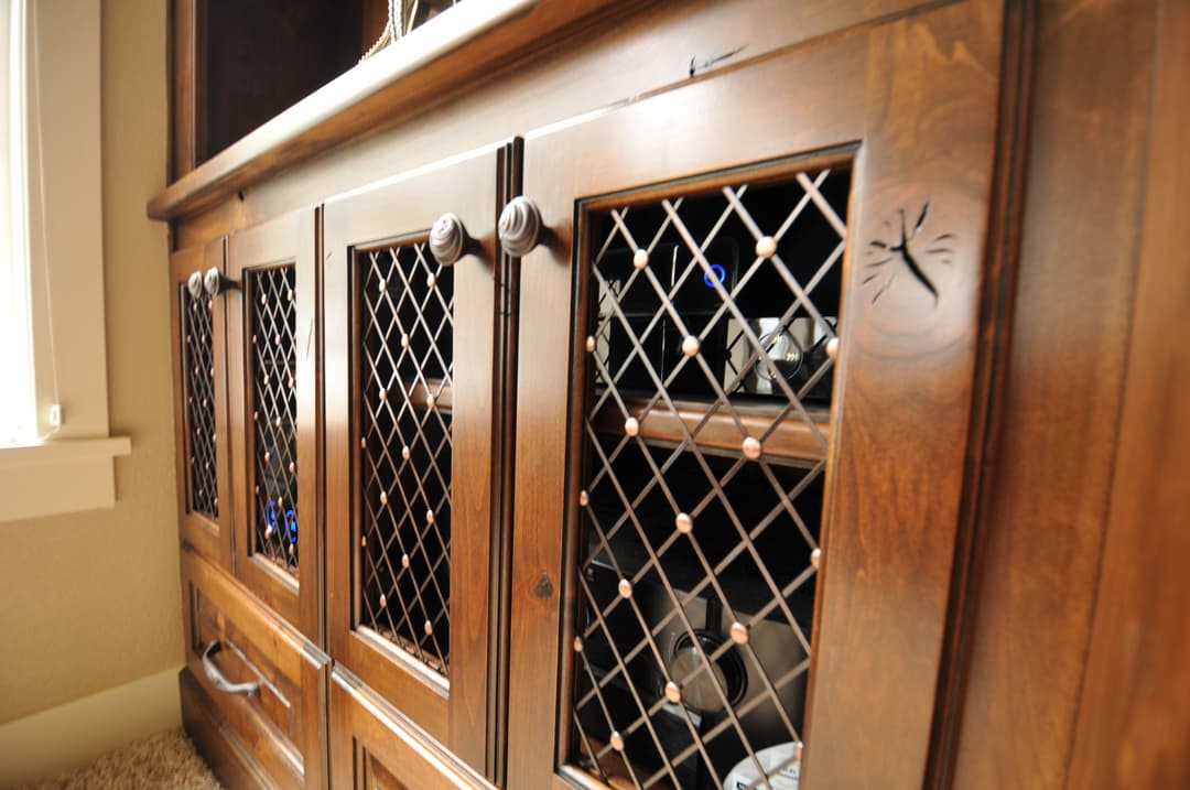 Wooden cabinet with lattice doors, showcasing wine bottles and decorative items inside.