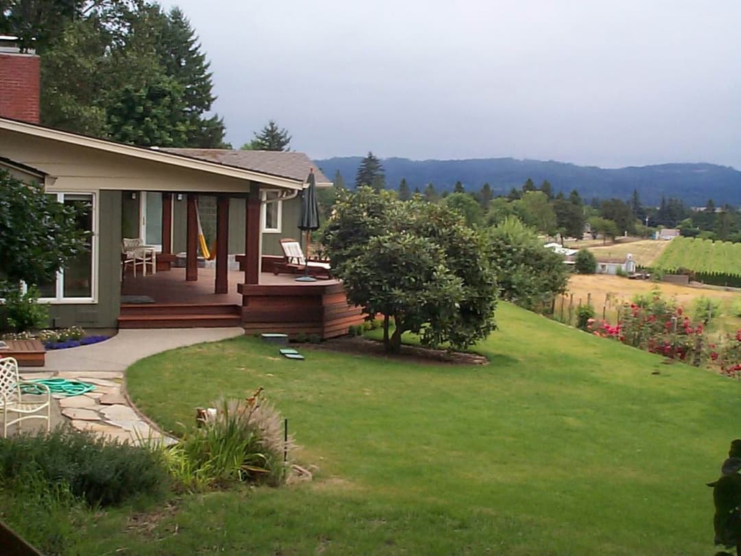 Scenic view of a home with a landscaped yard and mountains in the background.