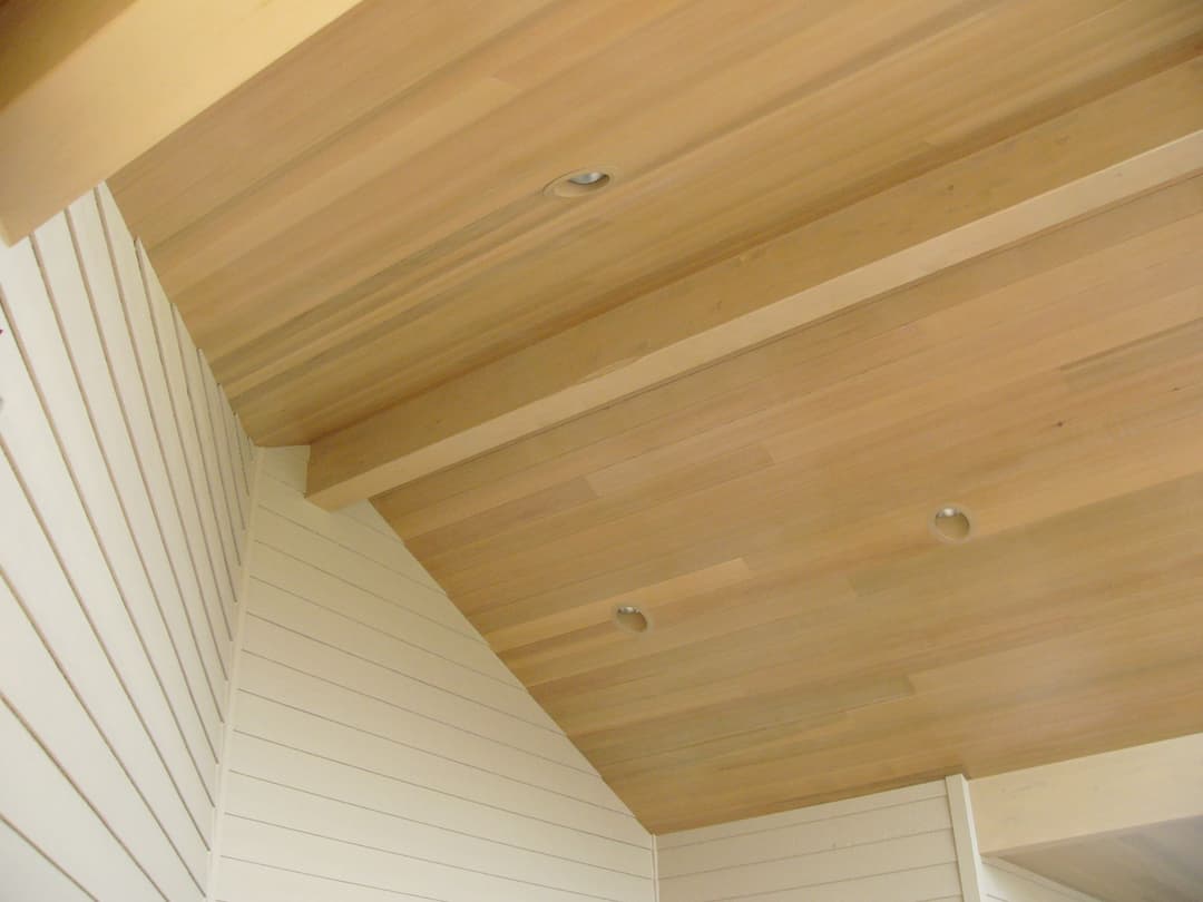 Wooden ceiling with recessed lighting and sloped design in modern interior space.