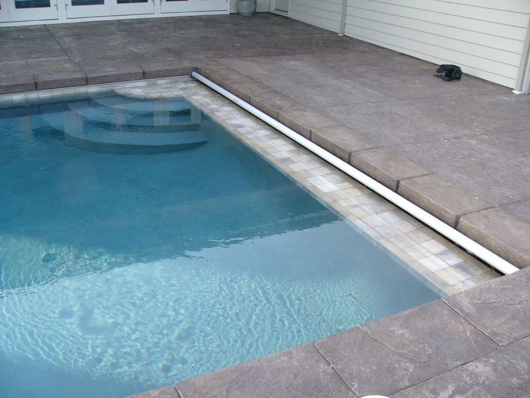 Swimming pool with clear water and tiled edge on a stone patio. Relaxing outdoor space.