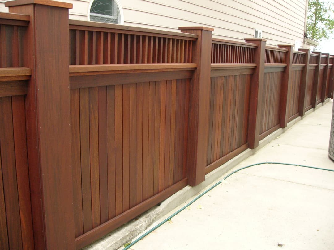 Wooden privacy fence along a residential walkway with vertical and horizontal slats.