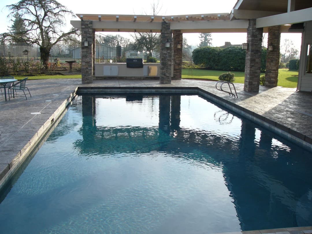 Luxury backyard with a sparkling pool, outdoor kitchen, and landscaped garden. Perfect for relaxation.