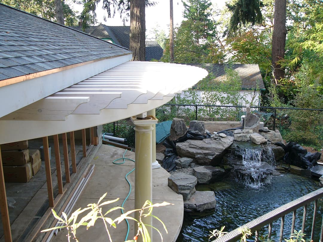Modern outdoor patio with a roof overhang and a tranquil pond featuring a waterfall.