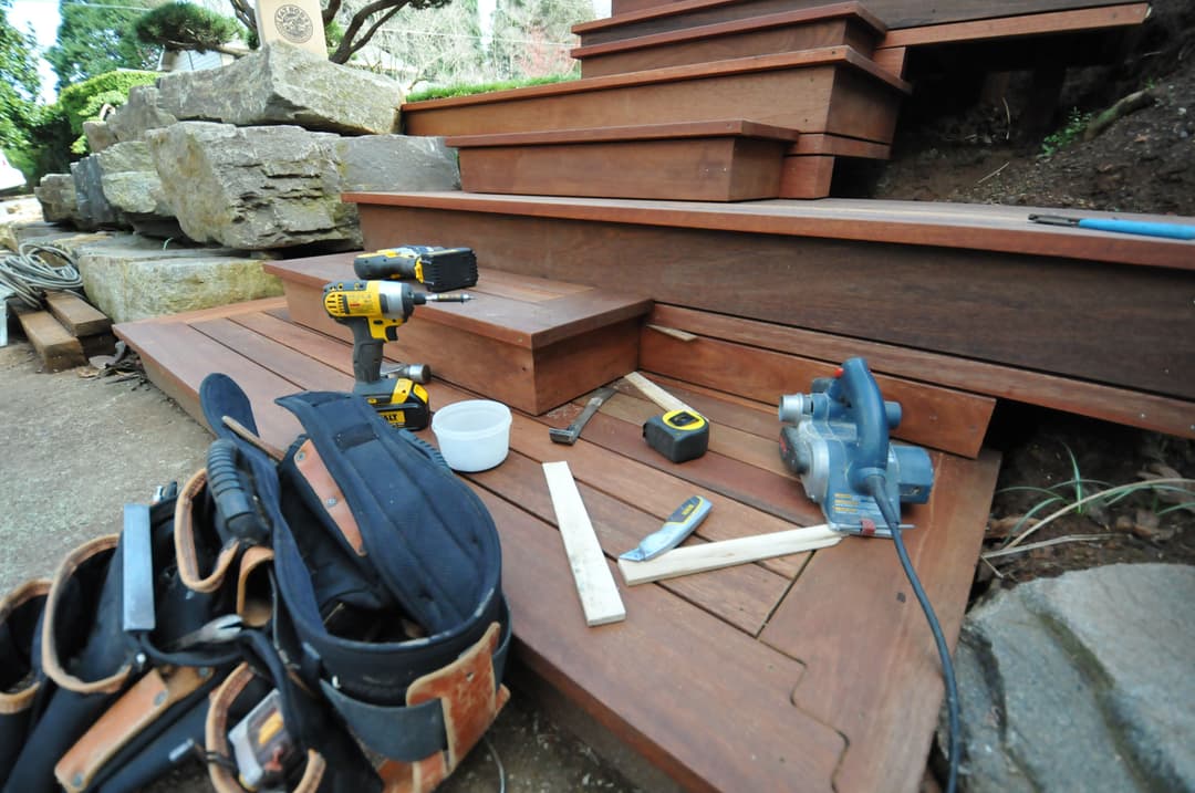 Woodworking tools and materials on outdoor wooden steps during a home renovation project.