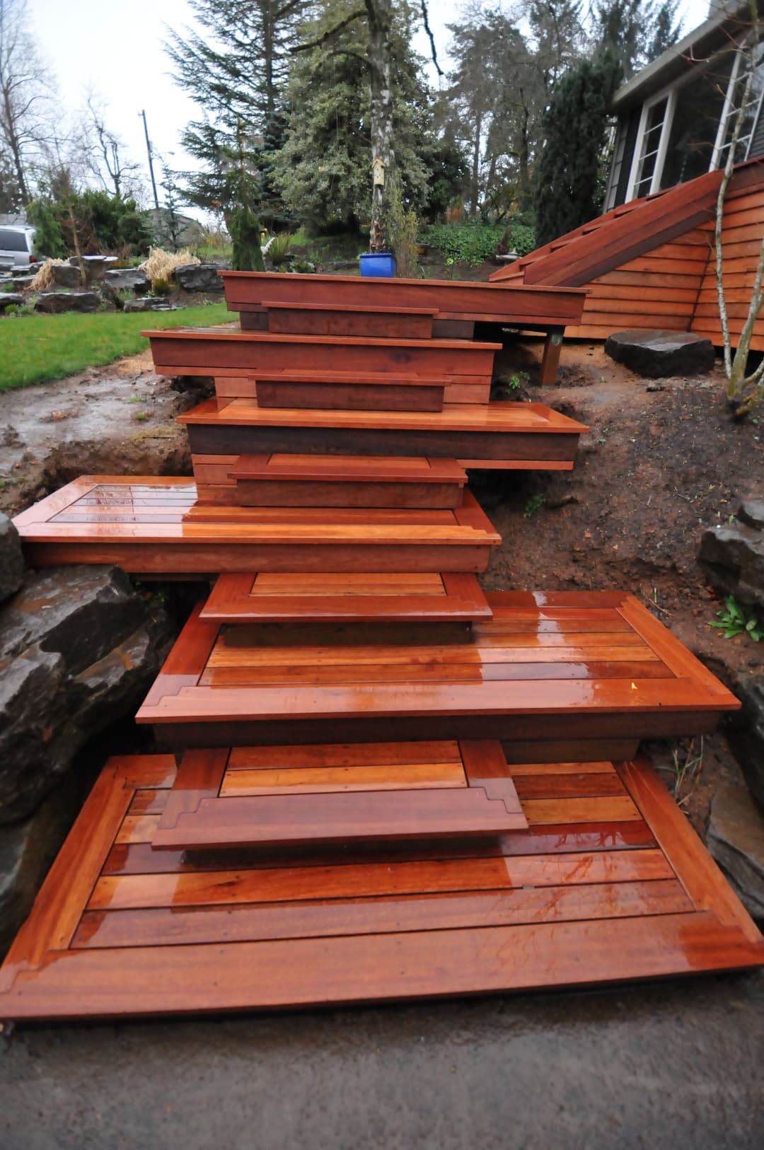 Wooden outdoor steps with polished finish, surrounded by landscaping and greenery.