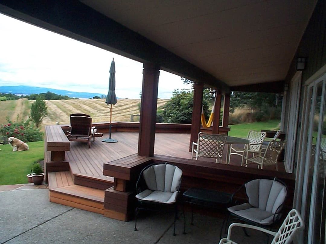 Spacious wooden deck overlooking a scenic landscape with a dog and patio furniture.