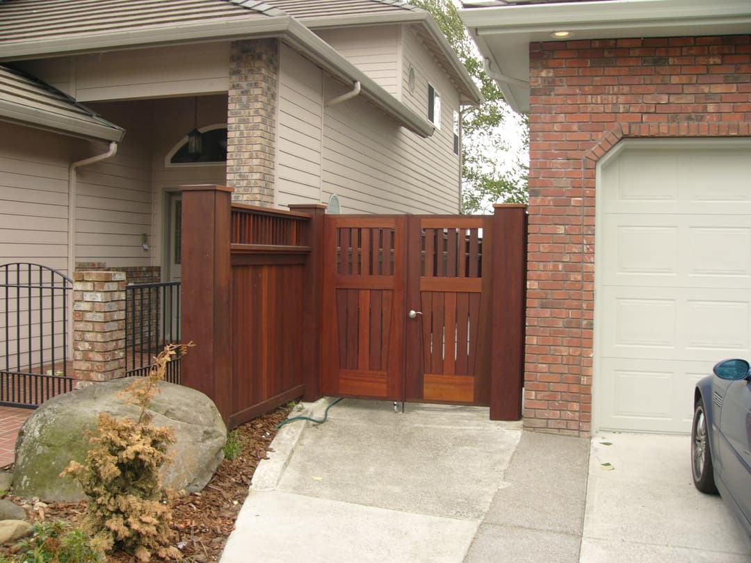 Wooden gate and fence design at a modern home entrance with stone landscaping.