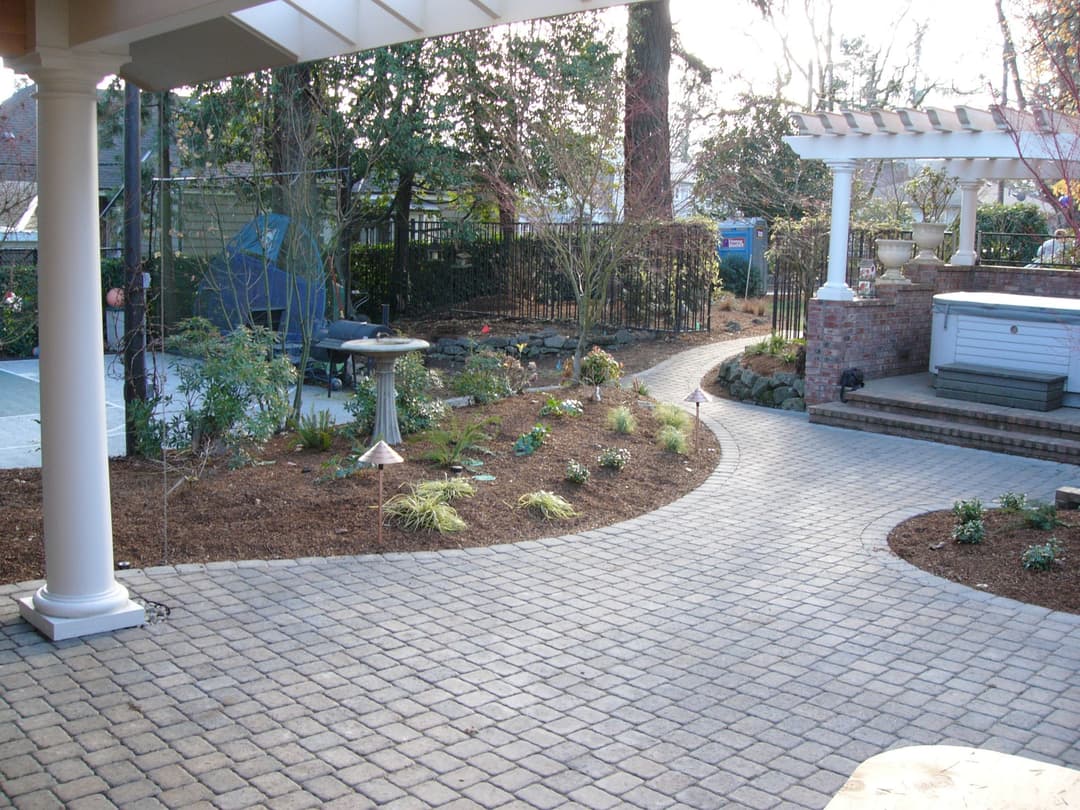 Beautifully landscaped garden with stone pathway, birdbath, and decorative plants.