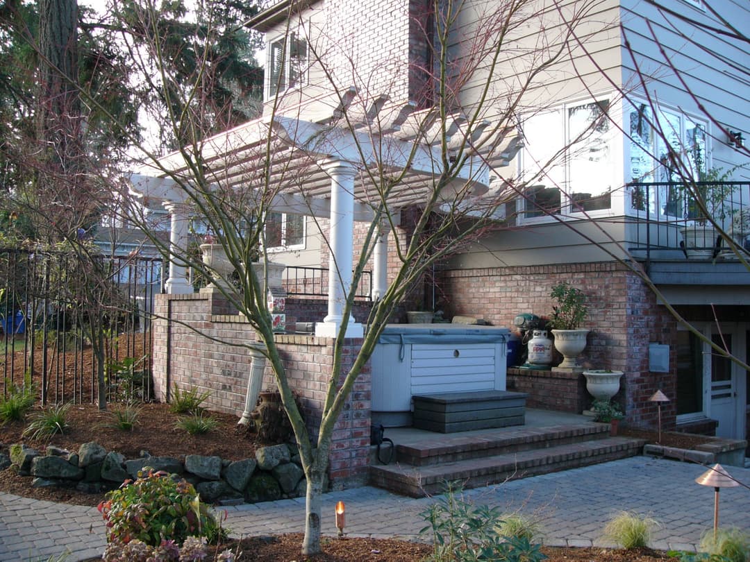 Elegant backyard patio with hot tub, brickwork, and landscaped garden features.