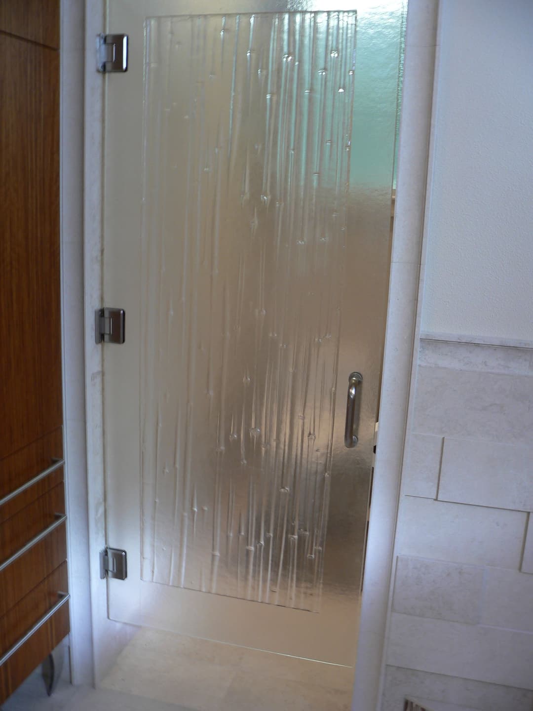 Frosted glass bathroom door with textured design and sleek silver handle.
