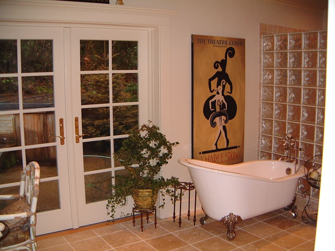 Elegant bathroom featuring a vintage clawfoot tub, glass brick wall, and decorative plant.
