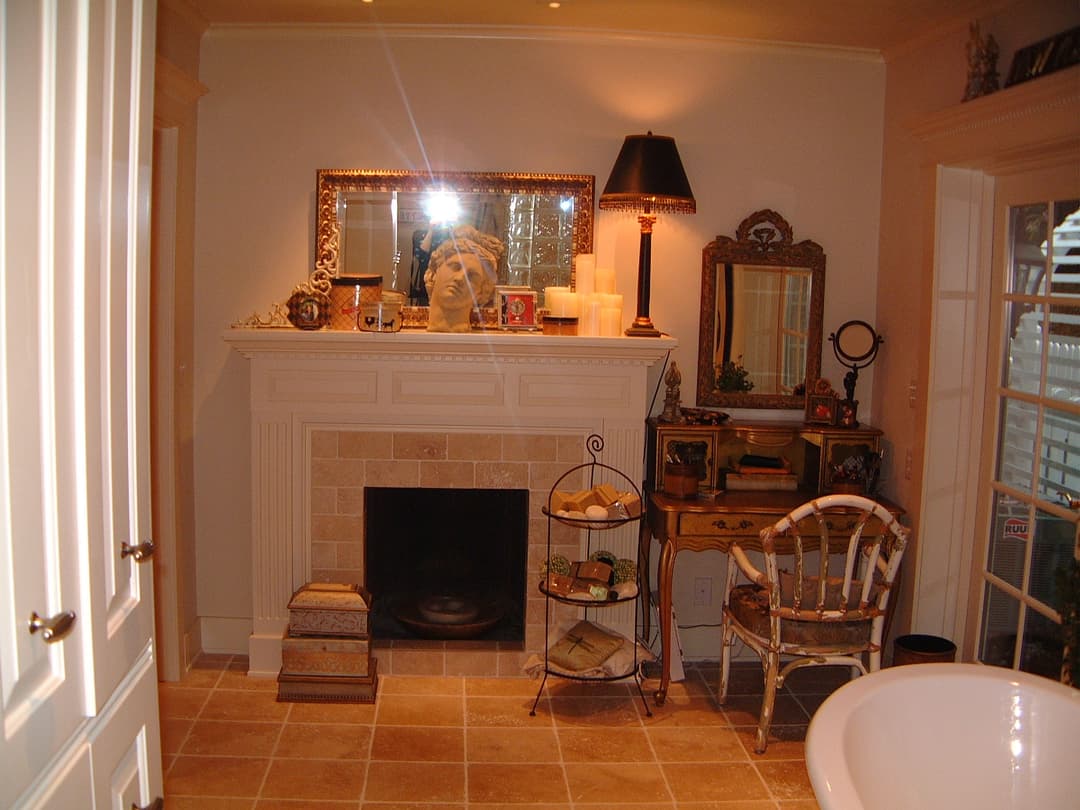 Cozy bathroom with a fireplace, vintage decor, and a mirror featuring a decorative statue.