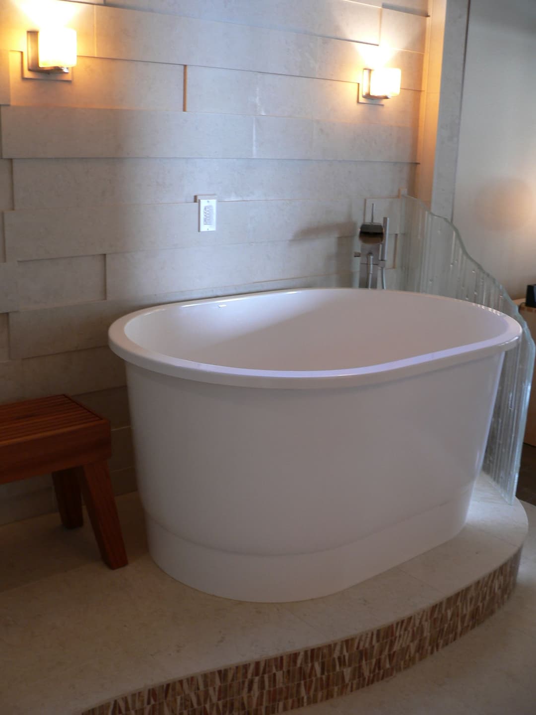 Elegant freestanding bathtub in modern bathroom design with stone wall and sleek lighting.